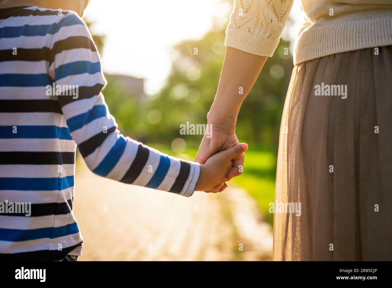 Nahaufnahme von Mutter und Sohn, die an sonnigen Tagen Händchen halten. Stockfoto