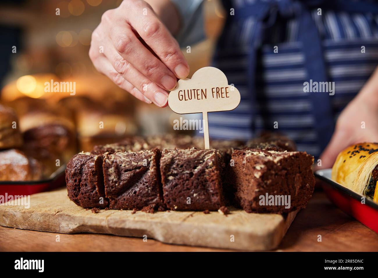 Verkaufsassistent In Der Bäckerei, Der Glutenfreie Etiketten In Frisch Gebackene Brownies Einfüllt Stockfoto