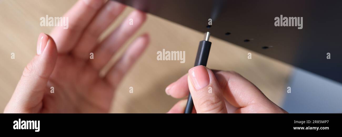 Person Hand verbindet ein schwarzes USB-C- oder Typ C-Netzkabel mit dem Computer Stockfoto
