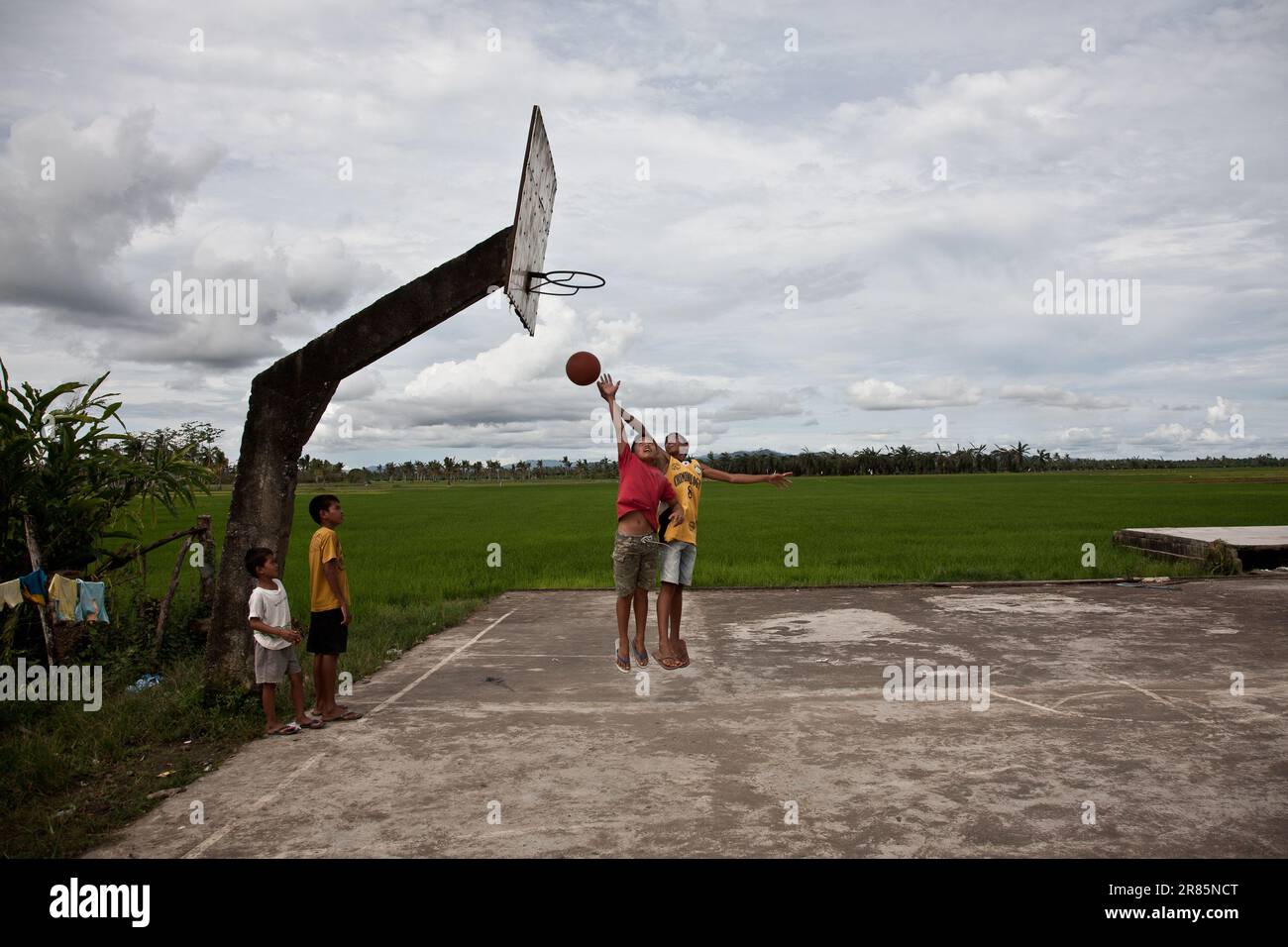 Kinder, die Basketball auf einem Platz an einem Reisfeld in Mindanao, Philippinen, spielen. Philippines ist Co-Moderator der FIBA Basketball-Weltmeisterschaft 2023. Stockfoto