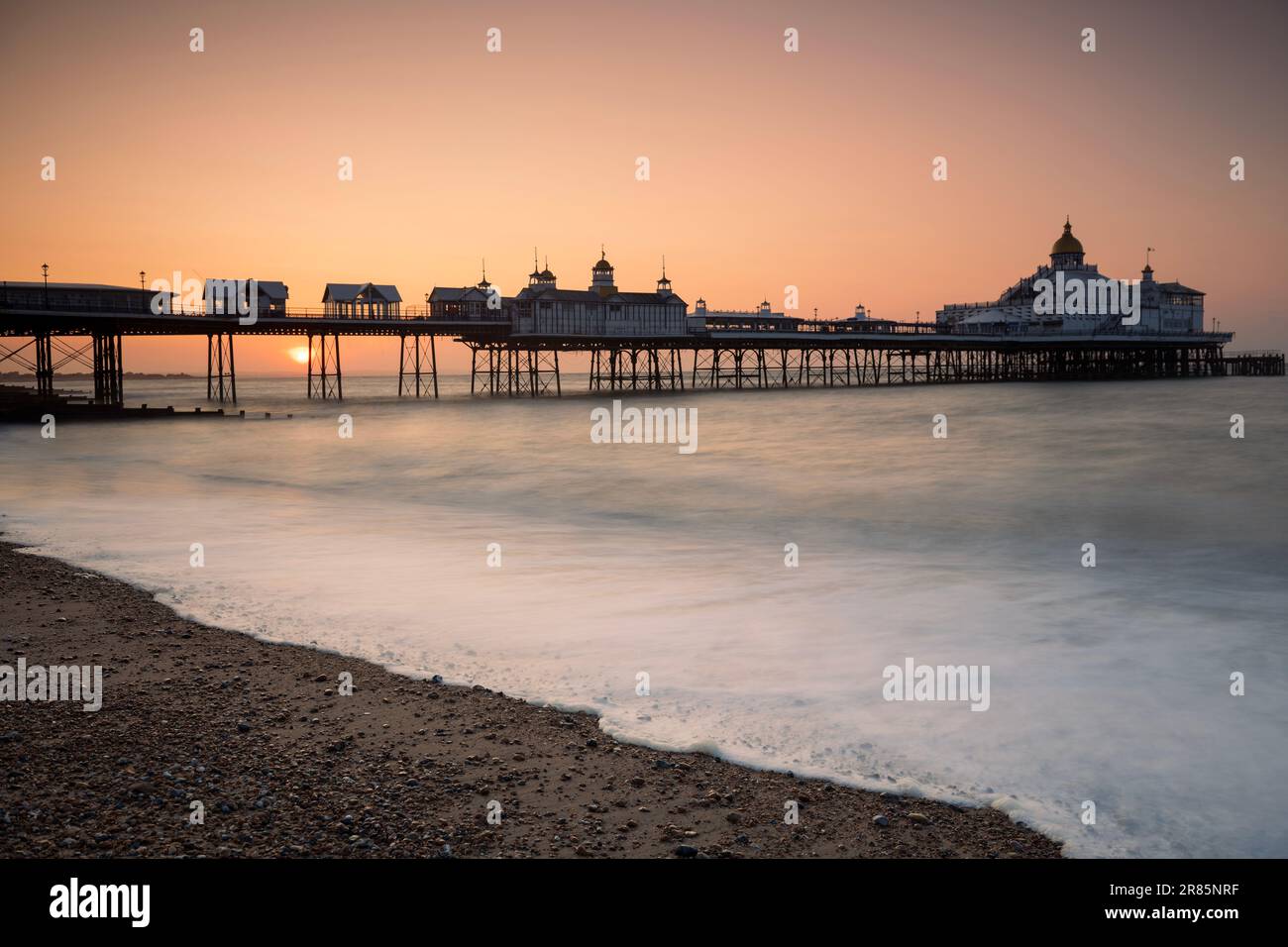 Goldene Farbtöne bei Sonnenaufgang: Die ruhelose Küste von Eastbourne, Sussex, England Stockfoto