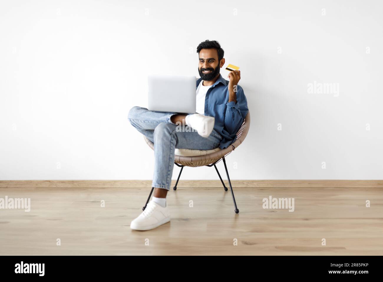 Arabic Guy Macht Einkaufen Mit Laptop Und Kreditkarte Drinnen Stockfoto