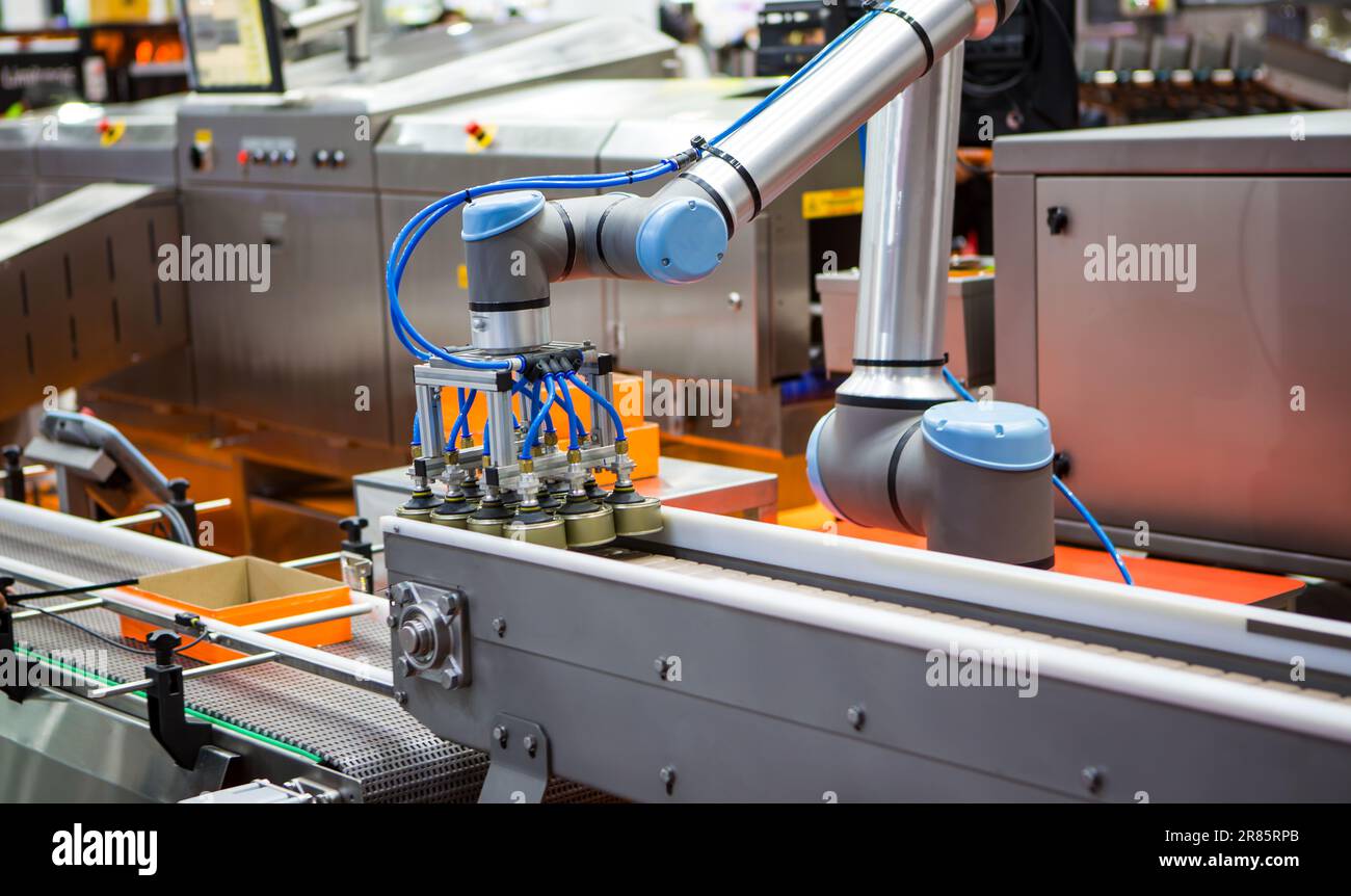 Automatisierter Roboterarm zum Anheben von Lebensmittelkannen zum Förderband in der Lebensmittelindustrie. Stockfoto