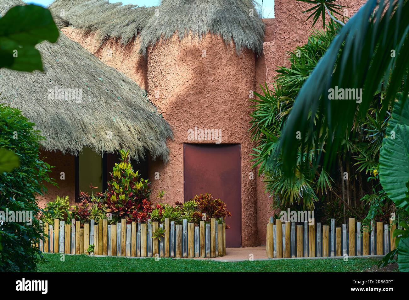 Schlammhaus mit Strohdach und einem wunderschönen Garten. Stockfoto