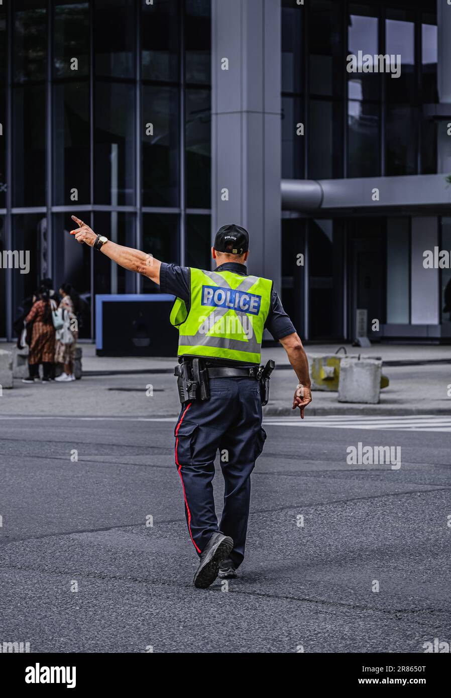 Ein Polizist leitet den Verkehr während der Hauptverkehrszeit in der Innenstadt von Toronto. Ein Polizist, der den Verkehr auf der Straße reguliert. Straßenfoto, Kopierbereich, Sel Stockfoto