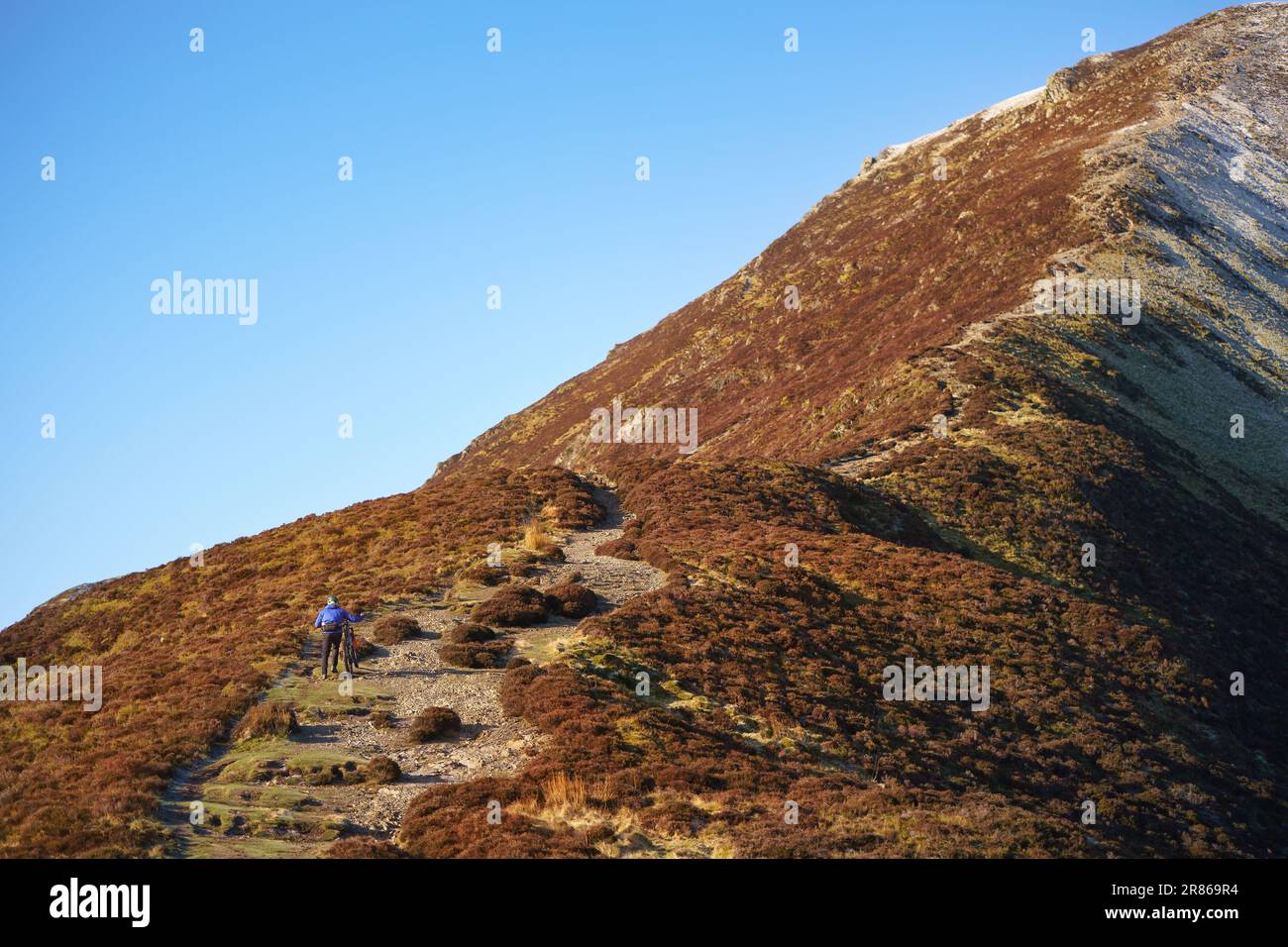 Ein Mountainbiker schiebt sein Fahrrad im englischen Lake District, Großbritannien, auf den Gipfel von Grisedale. Stockfoto