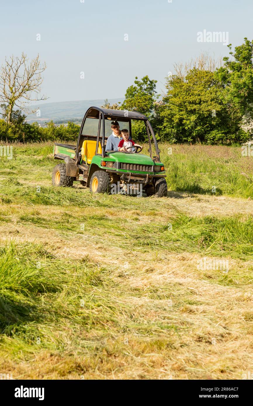 Sechs Jahre alter Junge, der einen John Deere Gator, High Bickington, North Devon, England, Großbritannien, taucht. Stockfoto