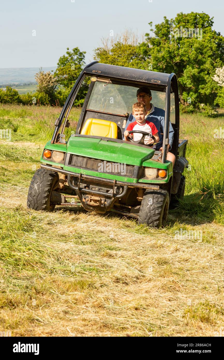 Sechs Jahre alter Junge, der einen John Deere Gator, High Bickington, North Devon, England, Großbritannien, taucht. Stockfoto