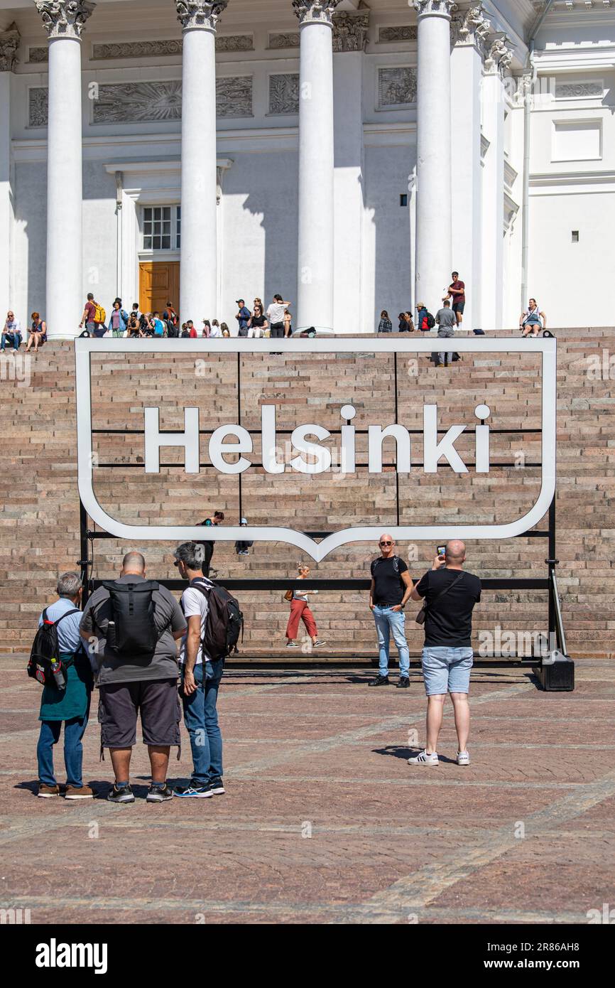 Touristen posieren vor dem großen Helsinki-Logo-Schild am Senatsplatz oder Senaatintori in Helsinki, Finnland Stockfoto