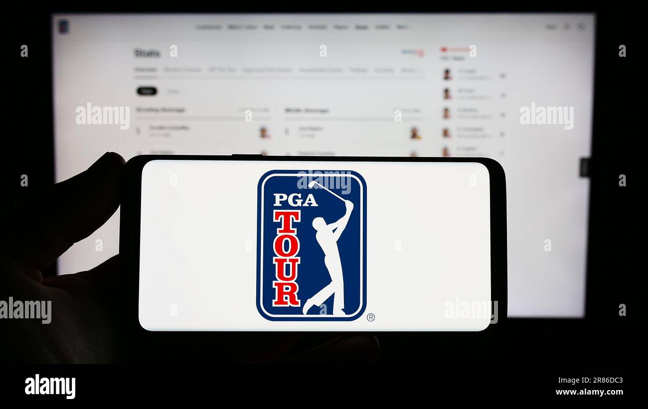 Person, die ein Smartphone mit dem Logo der US-Golforganisation PGA Tour auf dem Bildschirm vor der Website hält. Konzentrieren Sie sich auf das Display des Telefons. Stockfoto