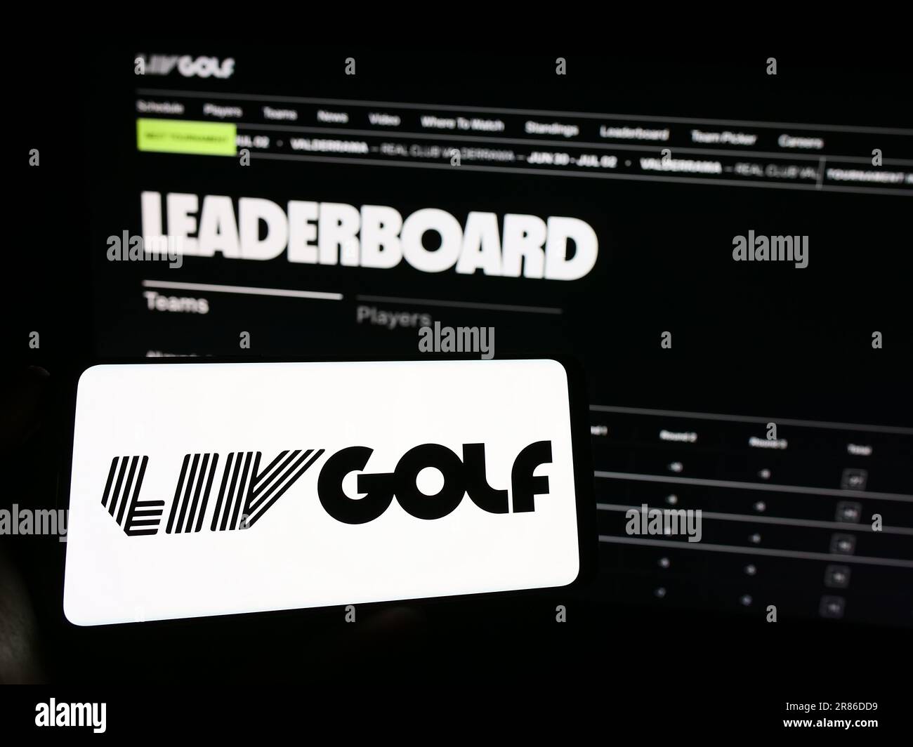 Person mit Handy mit Logo der Sportorganisation LIV Golf auf dem Bildschirm vor der Webseite. Konzentrieren Sie sich auf das Display des Telefons. Stockfoto