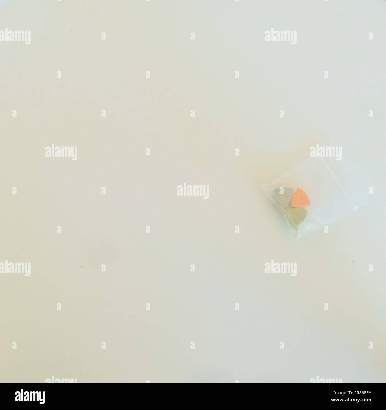 Ein Beutel mit Tesla Ecstasy-Pillen in Orange, Grün und Blau in Form eines Schilds mit dem Tesla Logo; 240 Milligramm MDMA Molly für die Freizeit. Stockfoto