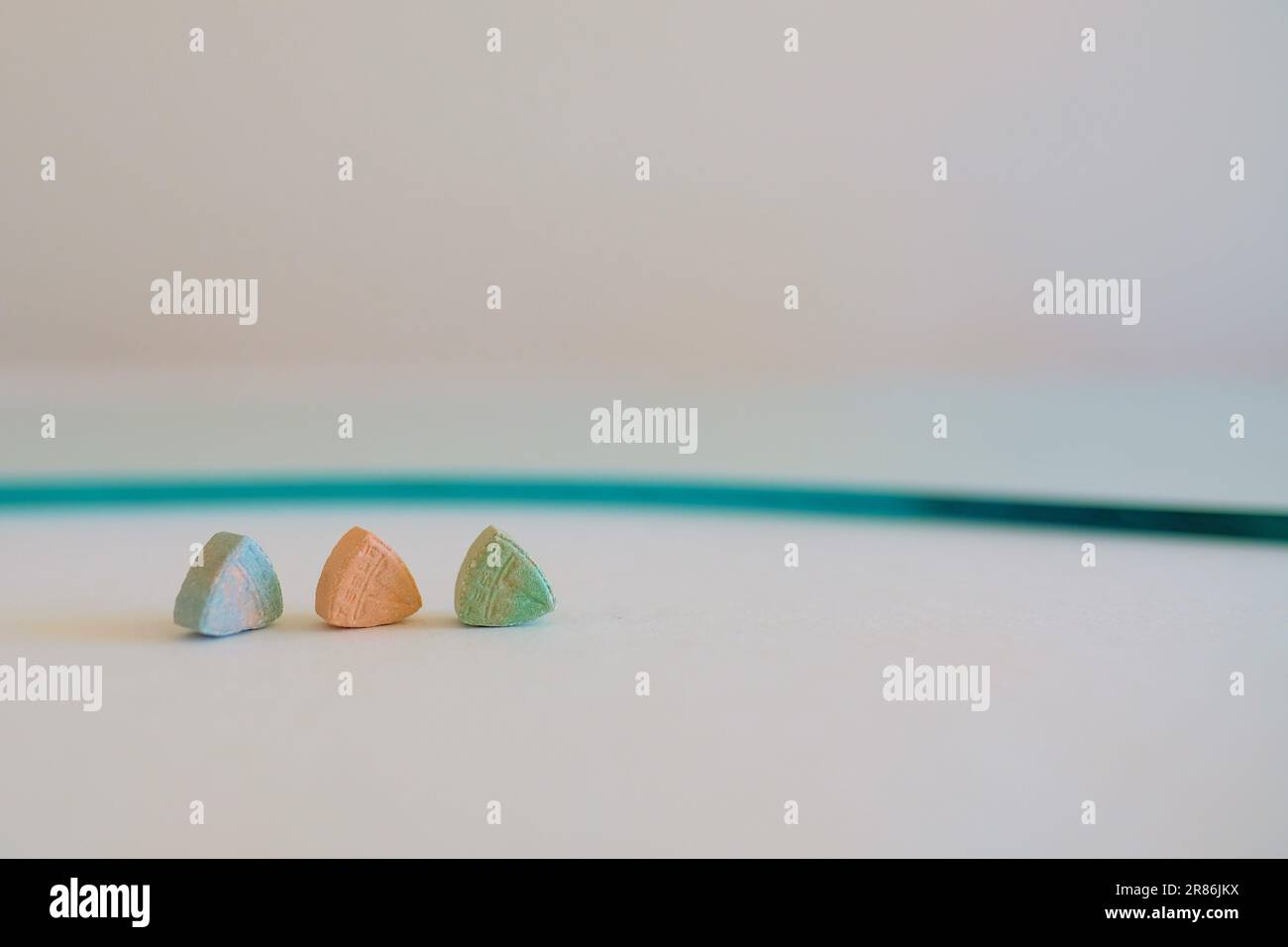 Tesla Ecstasy-Pillen in Orange, Grün und Blau, die wie ein Schild mit dem Tesla Logo geformt sind; 240 Milligramm Freizeit-MDMA oder Molly; Drogen Stockfoto