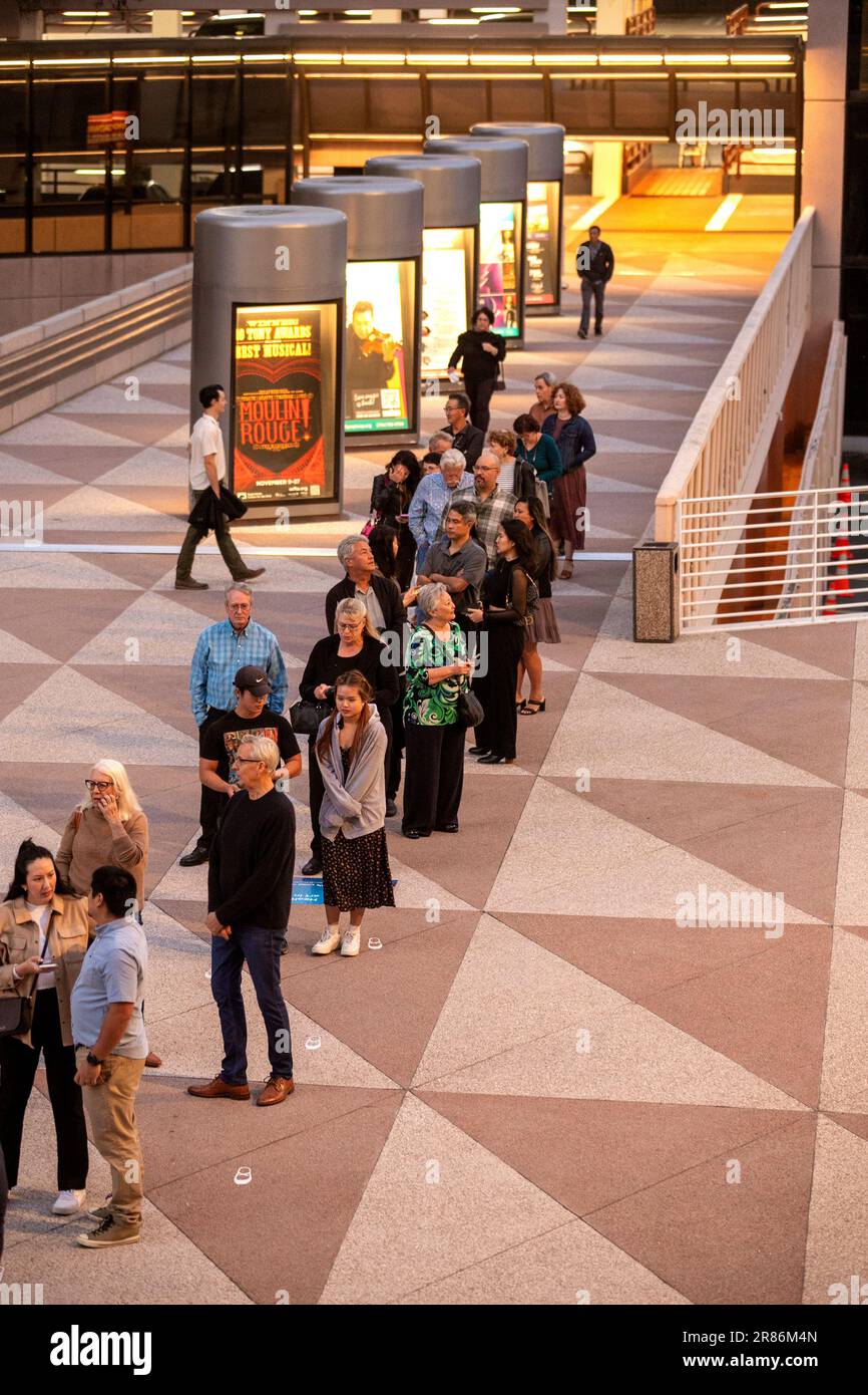 Die Zuschauer warten in der Schlange für ein Stück auf einer Fußgängerbrücke im Segerstrom Center for the Arts in Costa Mesa, CA. Beachten Sie die beleuchteten Poster. Stockfoto