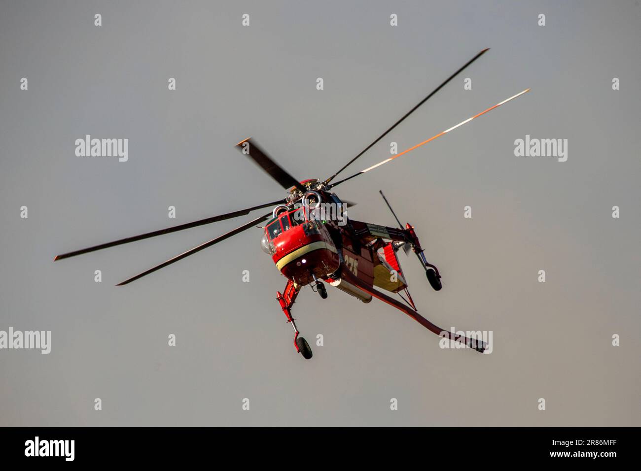 Ein Feuerwehrhubschrauber fliegt mit einem Wasserschlauch über ein Waldfeuer in einem Vorort in Laguna Niguel, Kalifornien. Stockfoto