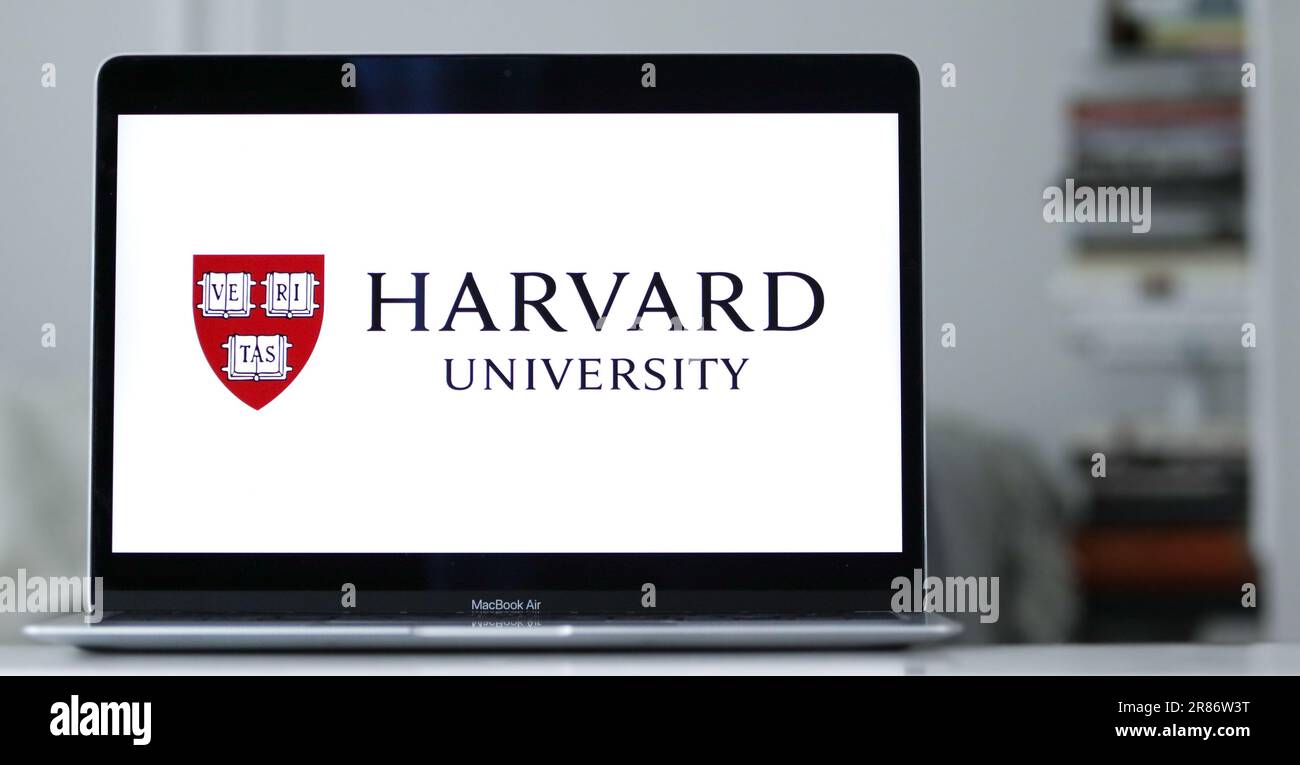 Ein MacBook Air liegt auf einem Schreibtisch auf, dessen Bildschirm das Logo der Harvard University zeigt Stockfoto