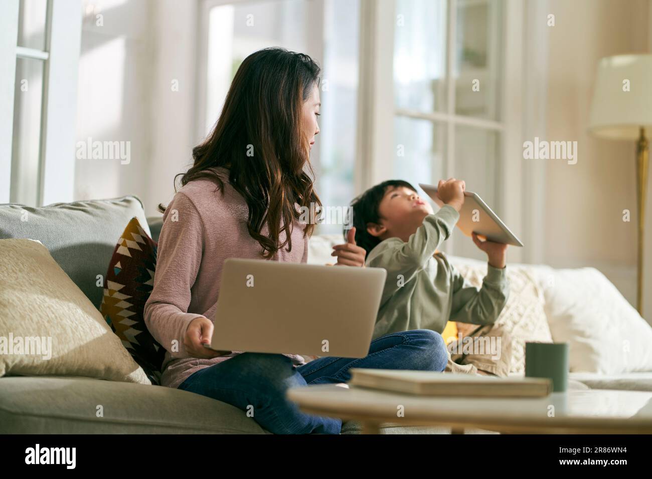 Junge asiatische Geschäftsfrau Mutter, die zu Hause arbeiten wollte, genervt von hyperaktivem Sohn Stockfoto