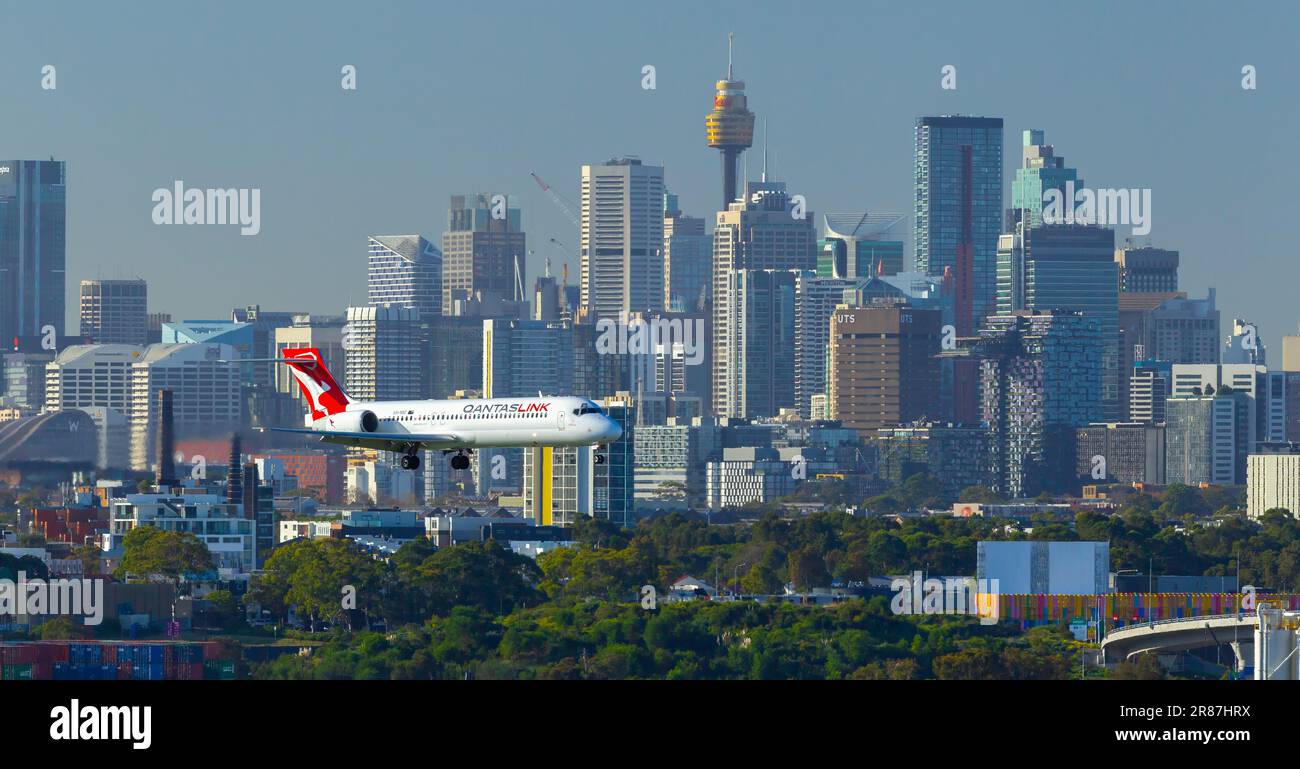 Ein Qantas Bombardier-Flugzeug mit VH-NXE-Registrierung, das am Sydney (Kingsford Smith) Airport in Sydney, Australien, landet, mit der Skyline von Sydney im Stockfoto