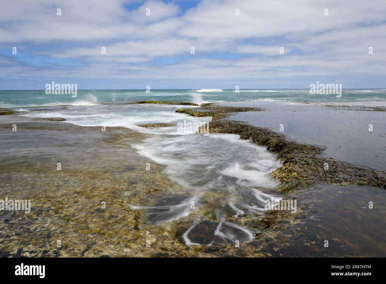 Gezeitenbecken, die bei Ebbe freigelegt werden und kleine Mini-Wasserfälle erzeugen Stockfoto