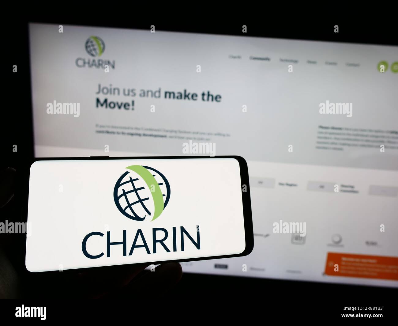 Person, die ein Mobiltelefon mit dem Logo der globalen CharIN e.V. auf dem Bildschirm vor der Webseite hält. Konzentrieren Sie sich auf das Display des Telefons. Stockfoto