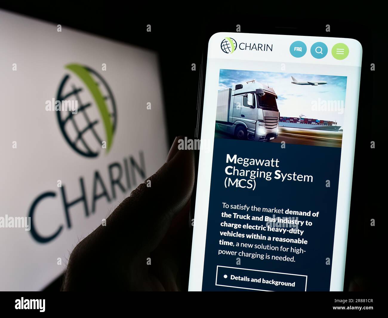 Person, die ein Mobiltelefon mit der Webseite der globalen CharIN e.V. auf dem Bildschirm vor dem Logo hält. Konzentrieren Sie sich auf die Mitte des Telefondisplays. Stockfoto