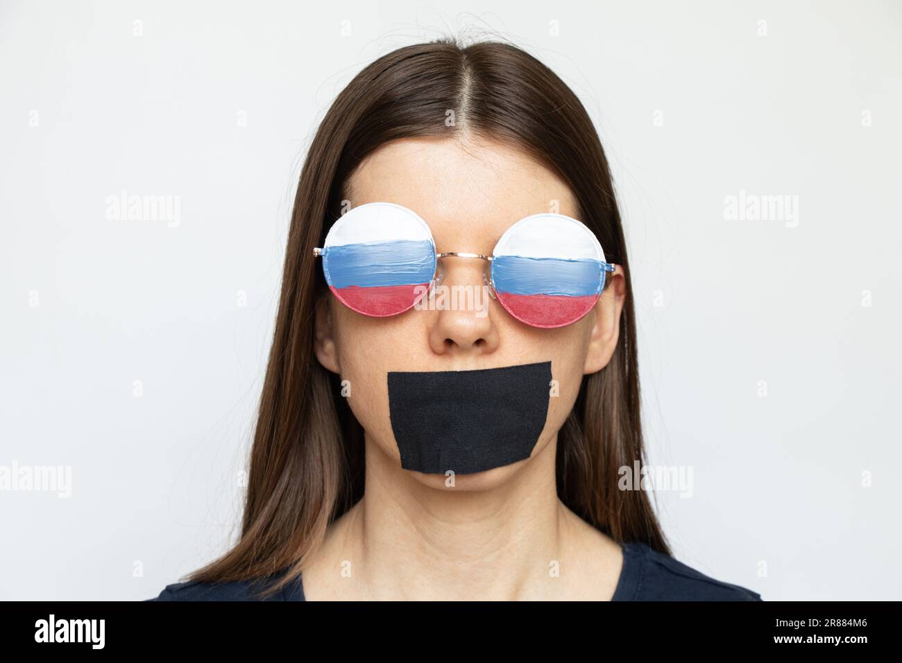 Russische Flagge auf der Brille eines Mädchens und ein Mund, versiegelt mit einem Verband auf weißem Hintergrund, taube, blinde und getäuschte Propaganda Russlands Stockfoto