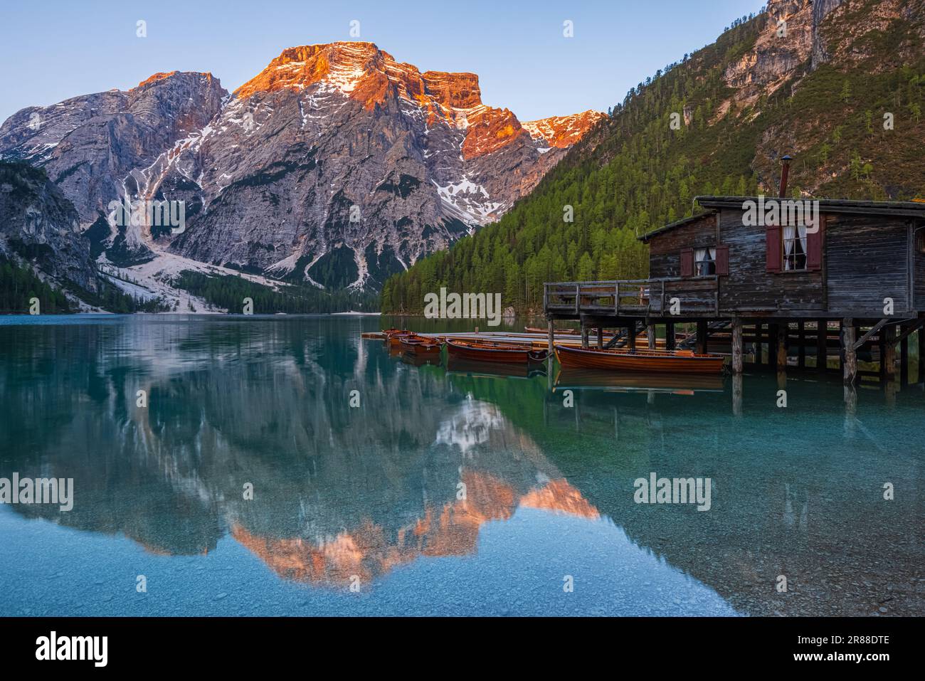 Ein Bild eines frühen Frühlingsmorgens bei Sonnenaufgang am Bootshaus und der berühmten Ruderboote am Pragser Wildsee (Lago di Braies), einem malerischen See i. Stockfoto