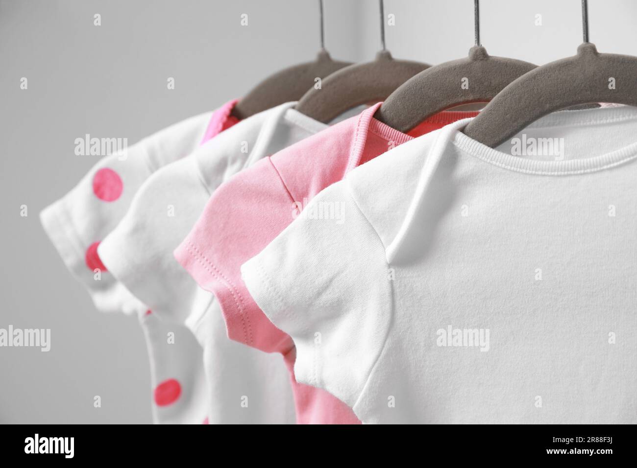 Kleiderbügel mit Babyanzügen auf weißem Hintergrund, Nahaufnahme Stockfoto