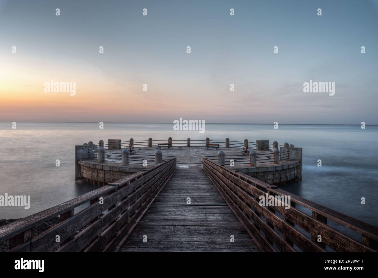 Am Morgen auf dem Pier und im Kreisverkehr mit Blick auf das Meer mit den herrlichen Farben des Sonnenaufgangs Stockfoto