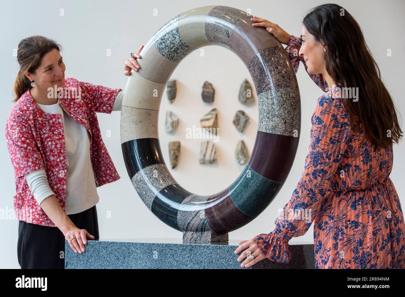 London, Großbritannien. 20. Juni 2023 Mitarbeiter mit „Torus der Zeit“, 2023, 16 Steine, beginnend mit Lewisian Gneiss, etwa 3 Milliarden Jahre alt, Und „Writed in Stone, Journey from the South Pole (xi)“, 2023, beginnend mit Lewisian Gneiss, ca. 3 Milliarden Jahre alt, und White Anorthosite, etwa 2,5 Milliarden Jahre alt (zurück), bei einer Vorschau von „Deep Time: Uncovering Our Hidden Past“, eine neue zeitgenössische Skulpturenausstellung von Angela Palmer in der Pangolin London Sculpture Gallery in der Nähe von King's Cross. Die Arbeiten beleuchten die drei Milliarden Jahre alte Geschichte des Vereinigten Königreichs durch seine Felsen und Steine. Die Show findet am 21. Juni statt Stockfoto
