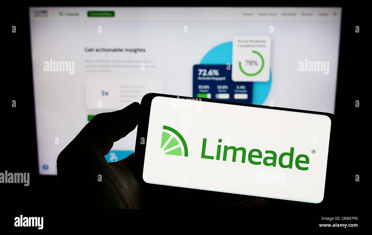 Person, die ein Mobiltelefon mit dem Logo des US-amerikanischen Mitarbeiter-Wohlfühlunternehmens Limeade Inc. Auf dem Bildschirm vor der Unternehmenswebseite hält. Konzentrieren Sie sich auf das Display des Telefons. Stockfoto