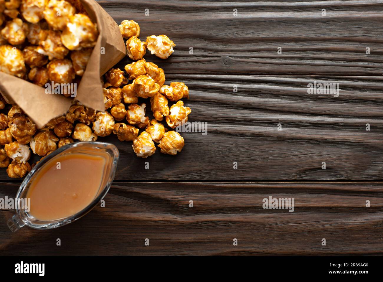 Karamellisiertes Popcorn in Papiertüte auf hölzernen Küchentisch flach legen Stockfoto