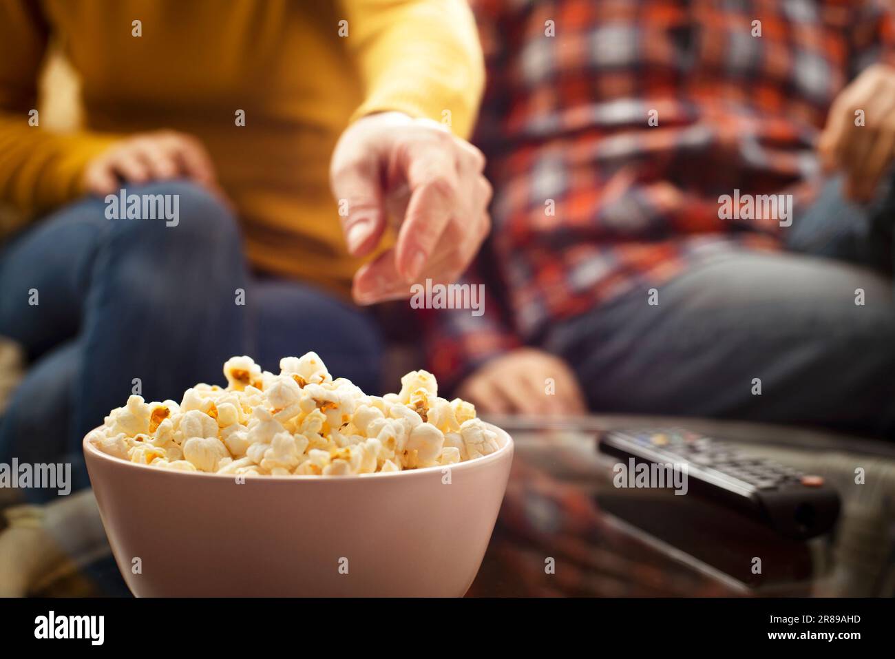 Kaukasisches Paar sitzt auf dem Sofa mit Popcorn und fernbedienung Stockfoto