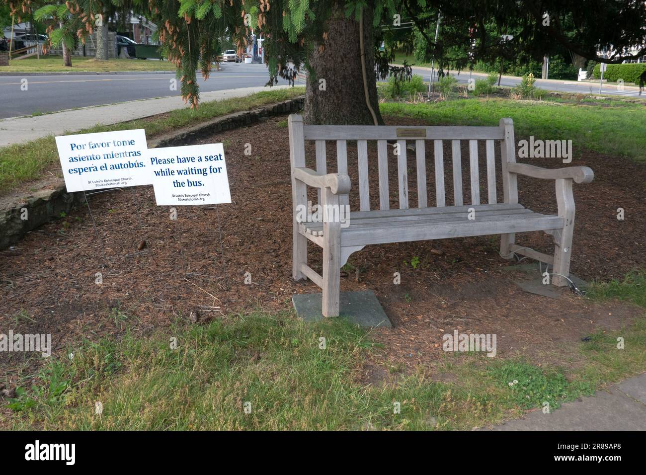 KLEINE STADT GASTFREUNDSCHAFT in einem Kirchhof gibt es 2 Schilder, die den Leuten einen Platz auf einer Bank bieten, während sie auf einen Bus warten. In Katonah, New York. Stockfoto