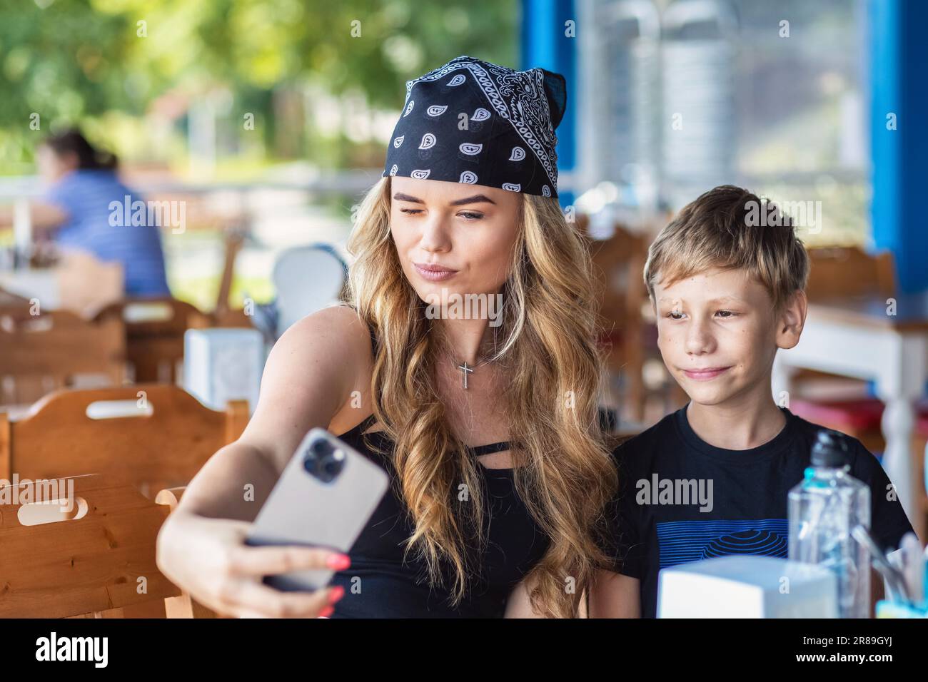 Coole Hipster-Mutter der Millennials macht Selfie, während sie mit ihrem wunderschönen Sohn im Restaurant lächelt Stockfoto