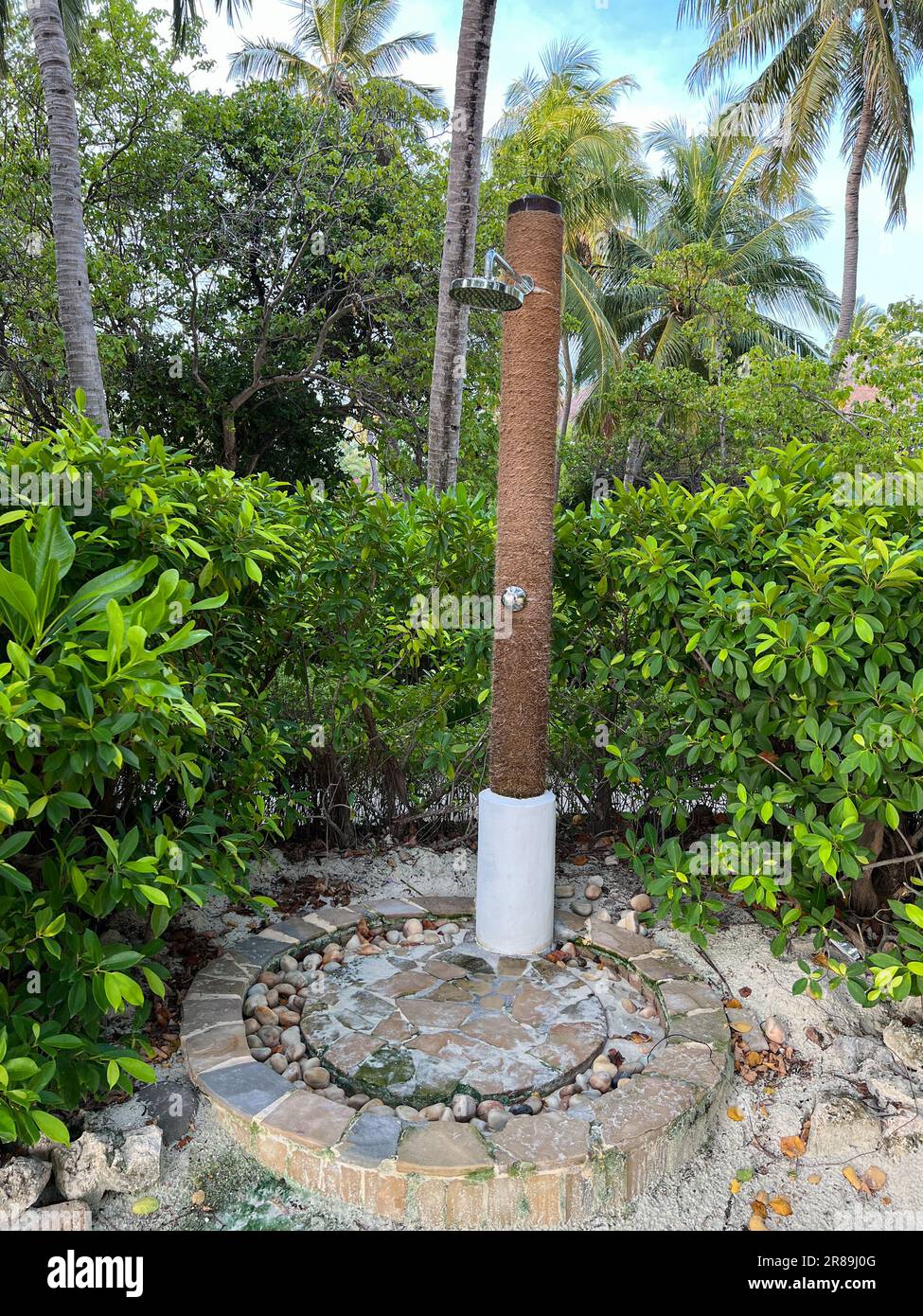 Außendusche am Strand mit üppiger grüner Vegetation rundherum. Stockfoto