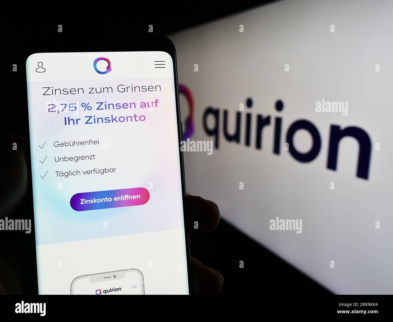 Person, die ein Smartphone mit einer Webseite des deutschen Finanzdienstleisters quirion AG auf dem Bildschirm mit Logo hält. Konzentrieren Sie sich auf die Mitte des Telefondisplays. Stockfoto