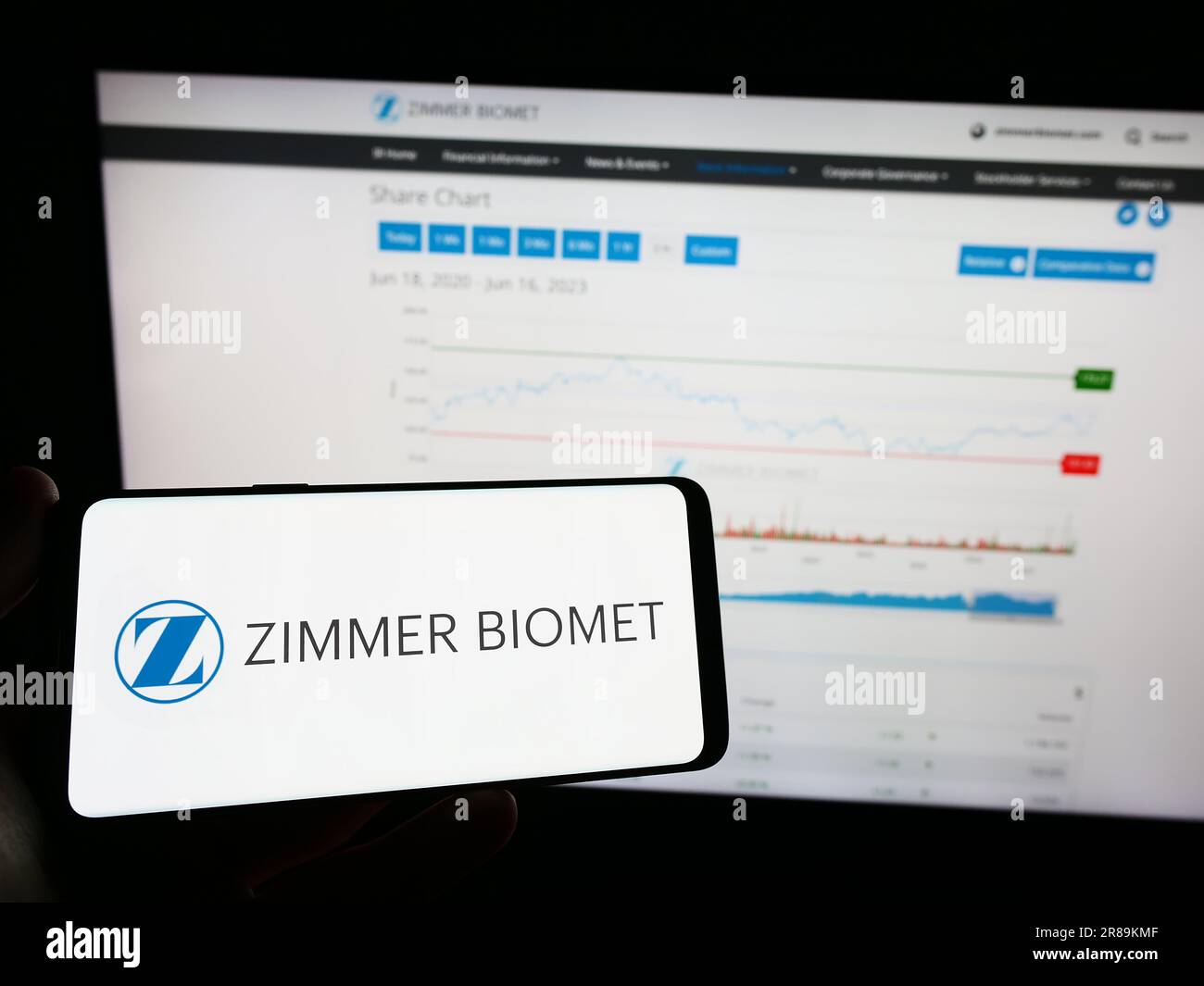 Person, die ein Mobiltelefon mit dem Logo der amerikanischen Firma Zimmer Biomet Holdings Inc. Auf dem Bildschirm vor der Webseite hält. Konzentrieren Sie sich auf das Display des Telefons. Stockfoto