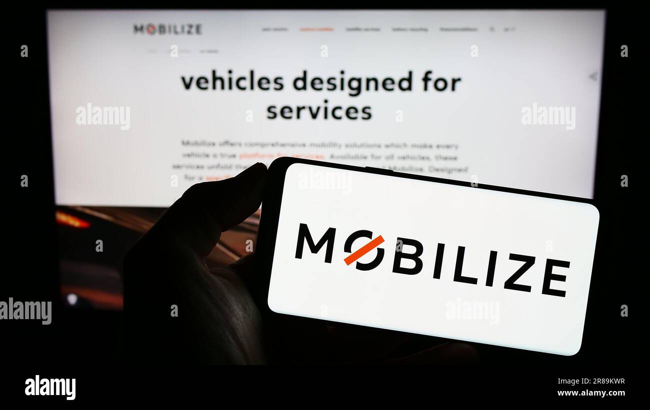 Person, die ein Mobiltelefon mit dem Logo des Unternehmens für Fahrzeugmobilität hält, mobilisiert sich vor der Webseite des Unternehmens auf dem Bildschirm. Konzentrieren Sie sich auf das Display des Telefons. Stockfoto