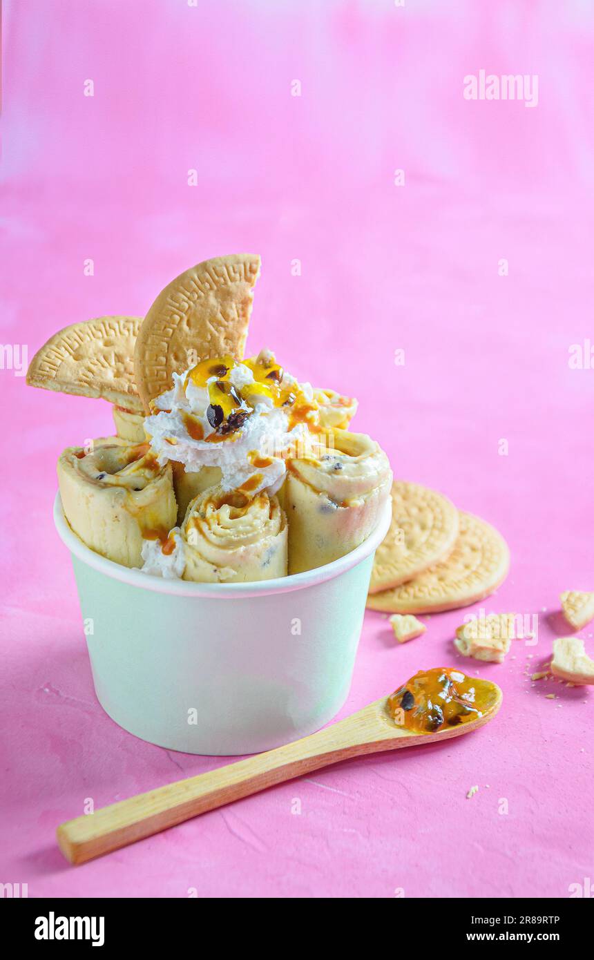 Parchita Pie Eiscreme Brötchen, mit chantilly Creme, Passionsfruchtsirup, auf pinkfarbenem Hintergrund Stockfoto