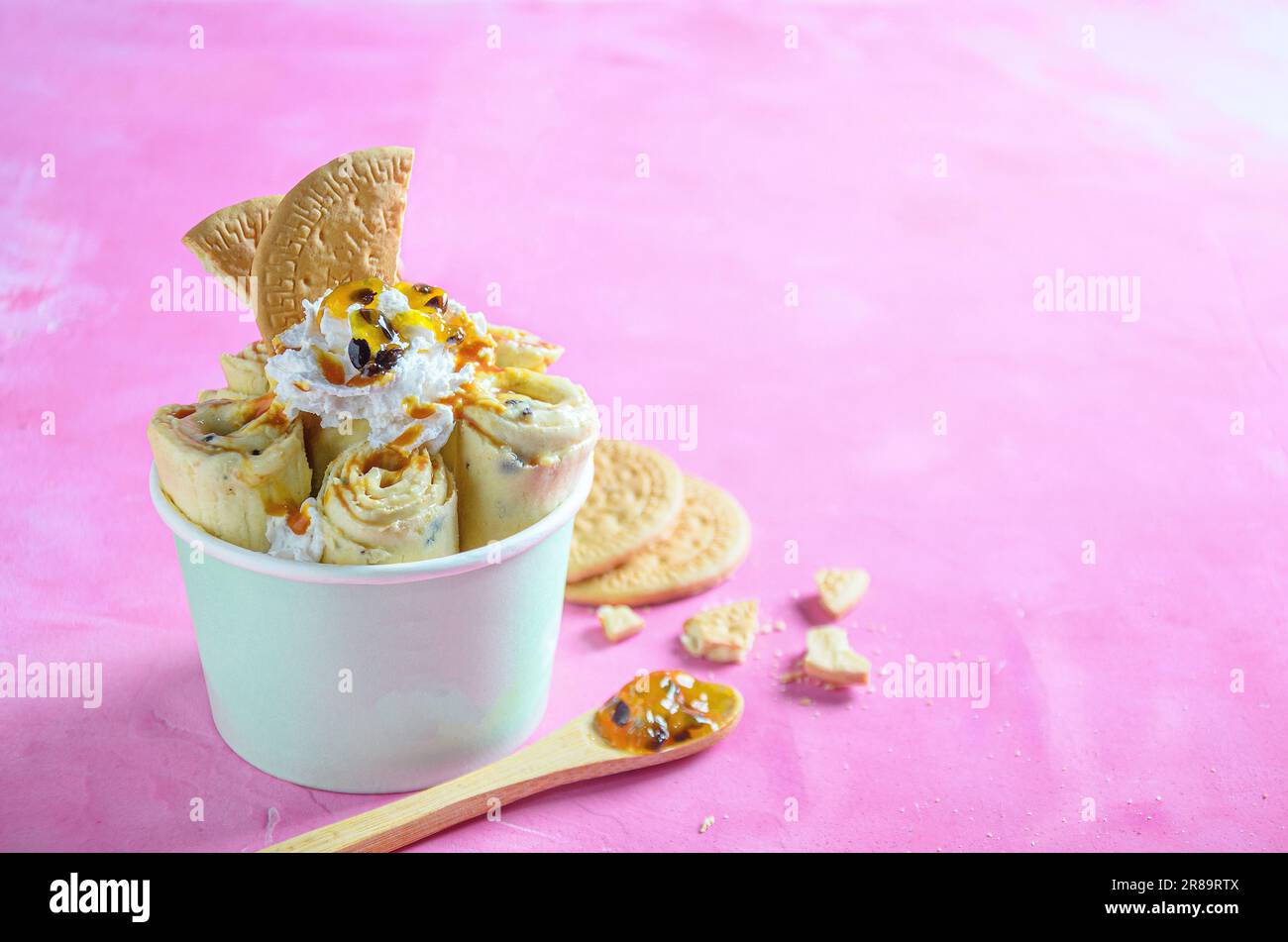 Parchita Pie Eiscreme Brötchen, mit chantilly Creme, Passionsfruchtsirup, auf pinkfarbenem Hintergrund Stockfoto