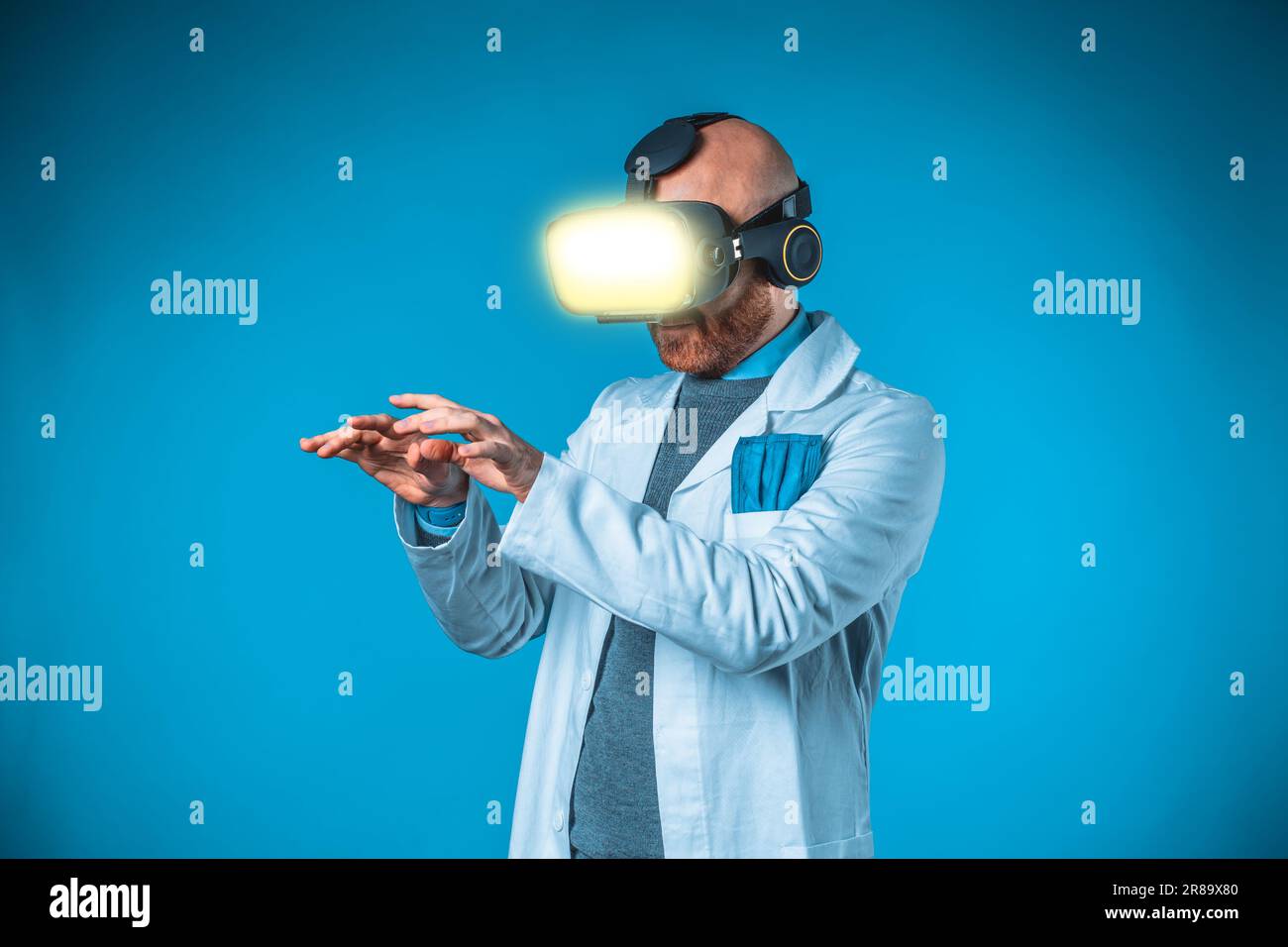 Foto eines männlichen Arztes mit 3D-Brille mit blauem Hintergrund und medizinischem weißem Kittel Stockfoto