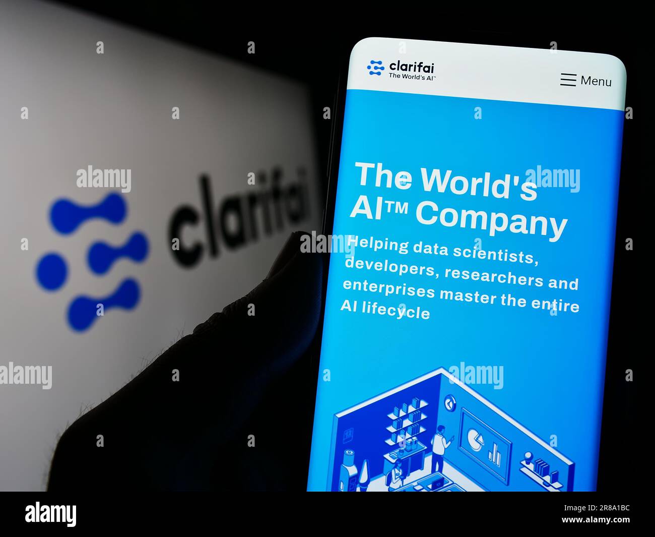 Person, die ein Mobiltelefon mit einer Webseite des US-amerikanischen Unternehmens Clarifai Inc. Für künstliche Intelligenz auf dem Bildschirm mit Logo hält. Konzentrieren Sie sich auf die Mitte des Telefondisplays. Stockfoto