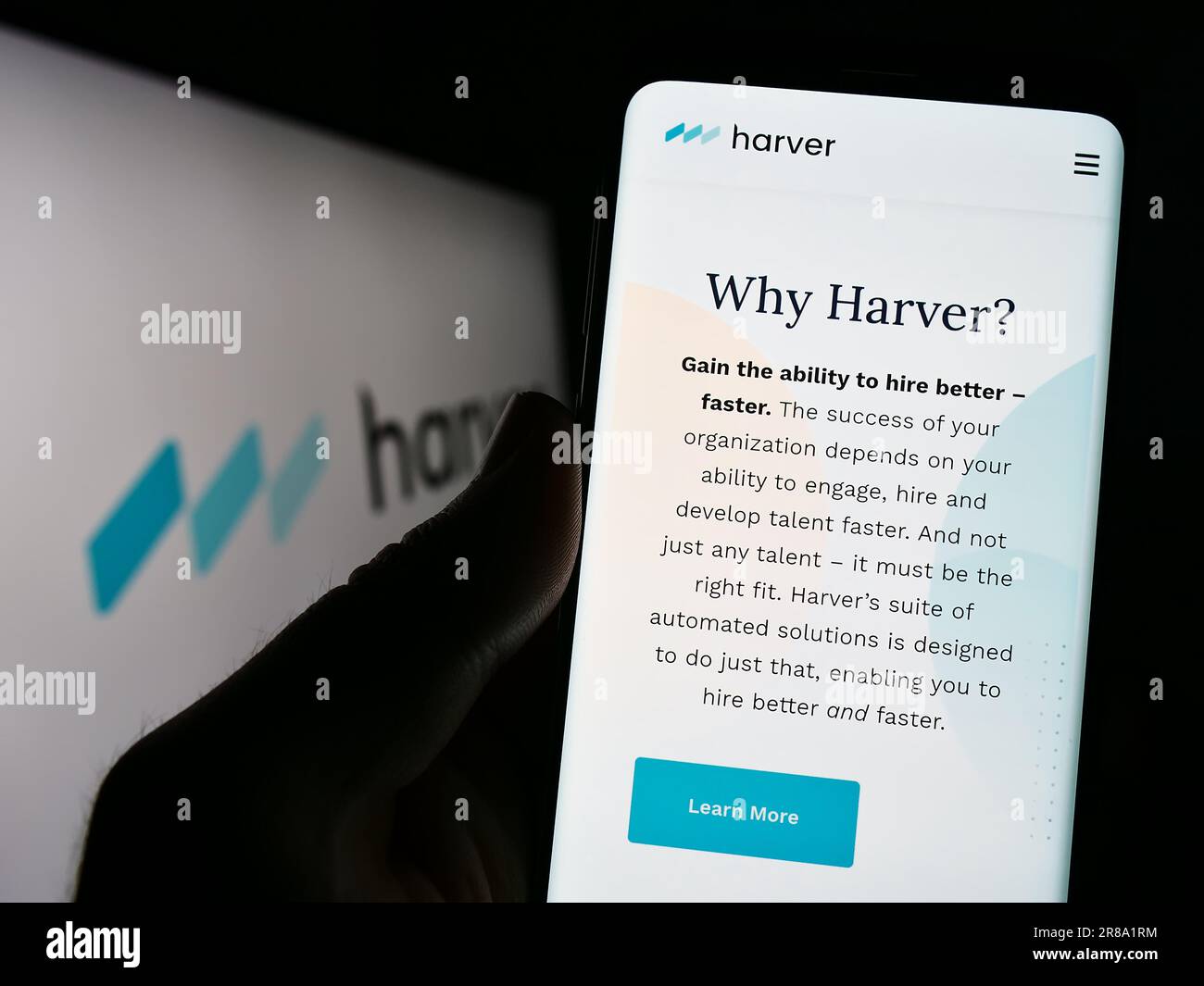 Person, die ein Mobiltelefon mit einer Webseite des Talent-Management-Unternehmens Harver B.V. auf dem Bildschirm mit Logo hält. Konzentrieren Sie sich auf die Mitte des Telefondisplays. Stockfoto