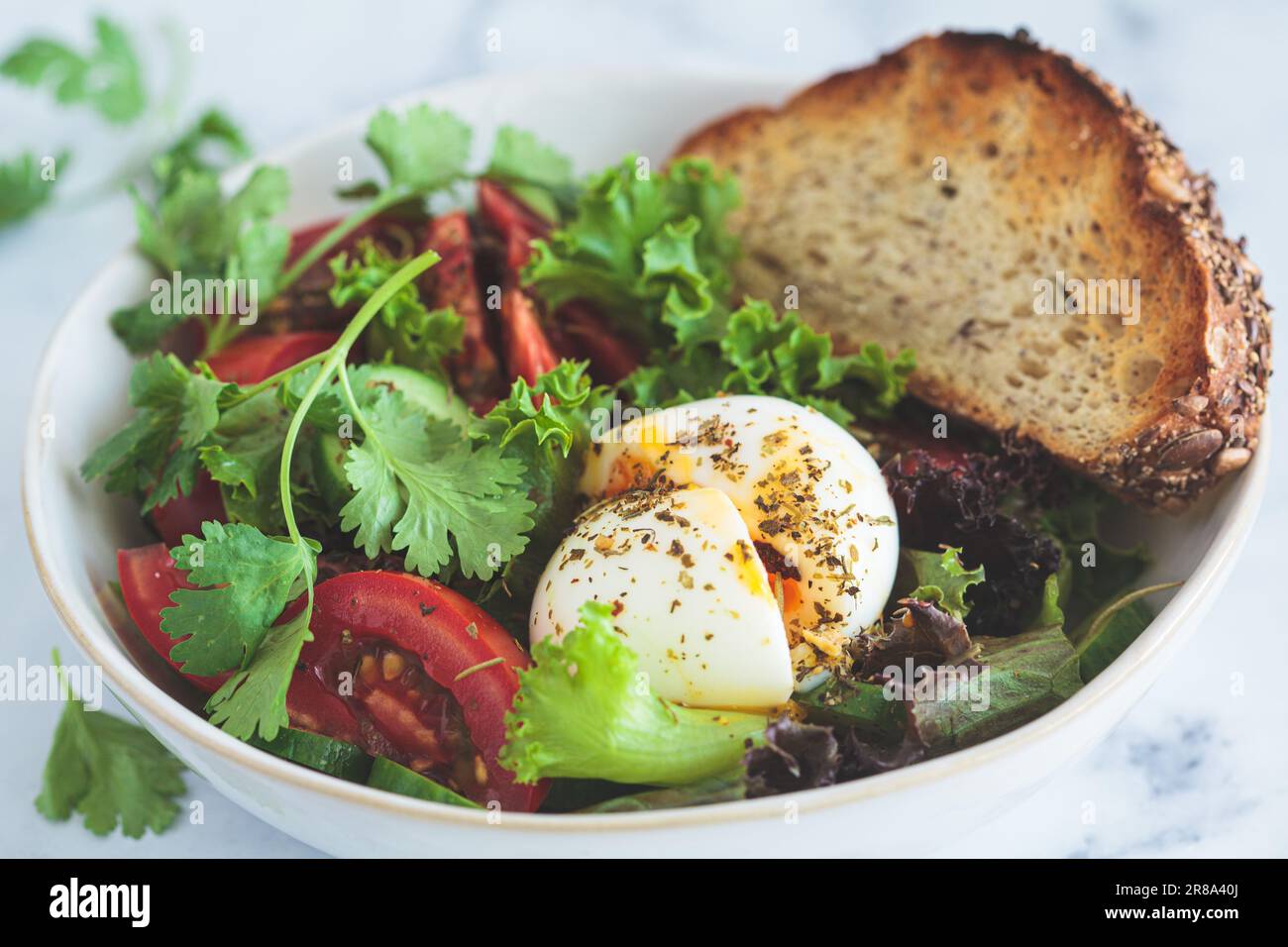 Gemüsesalatschüssel mit Eiern und Vollkorntoast zum Frühstück, weißer Hintergrund, Nahaufnahme. Stockfoto
