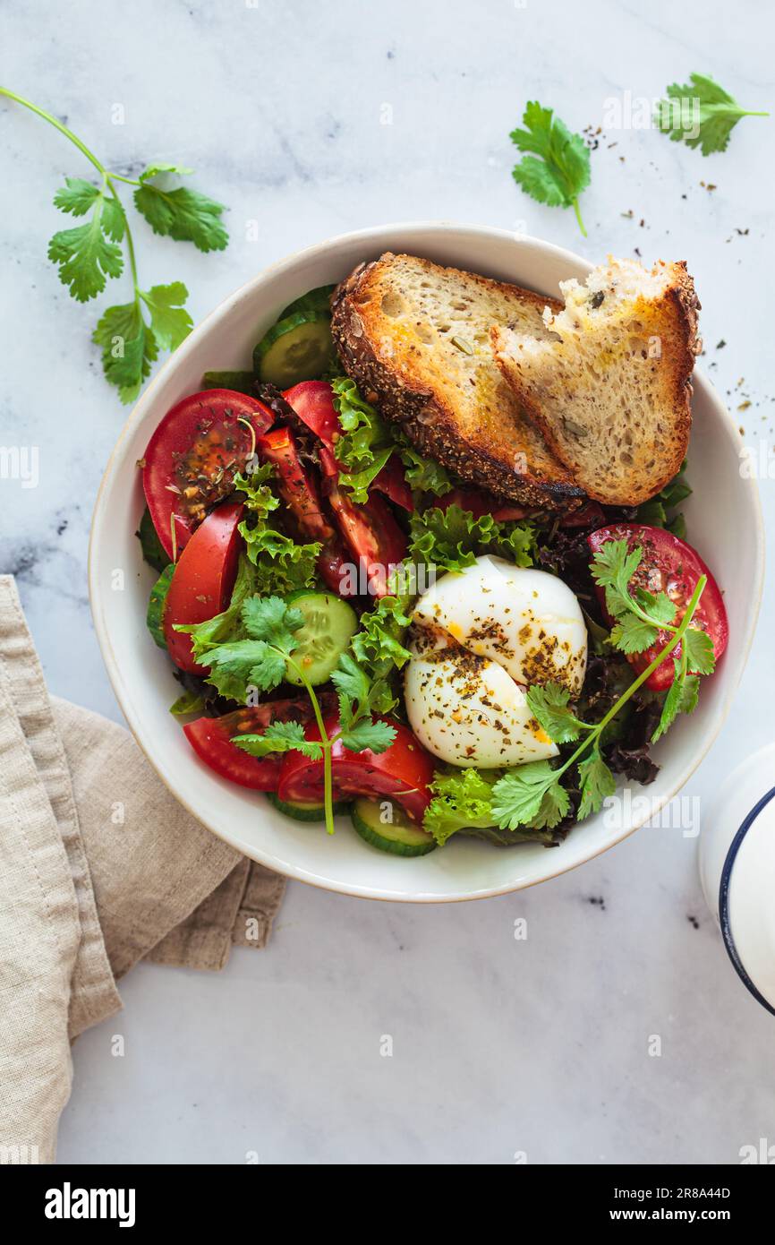 Gemüsesalatschüssel mit Eiern und Vollkorntoast zum Frühstück, weißer Hintergrund, Draufsicht. Stockfoto