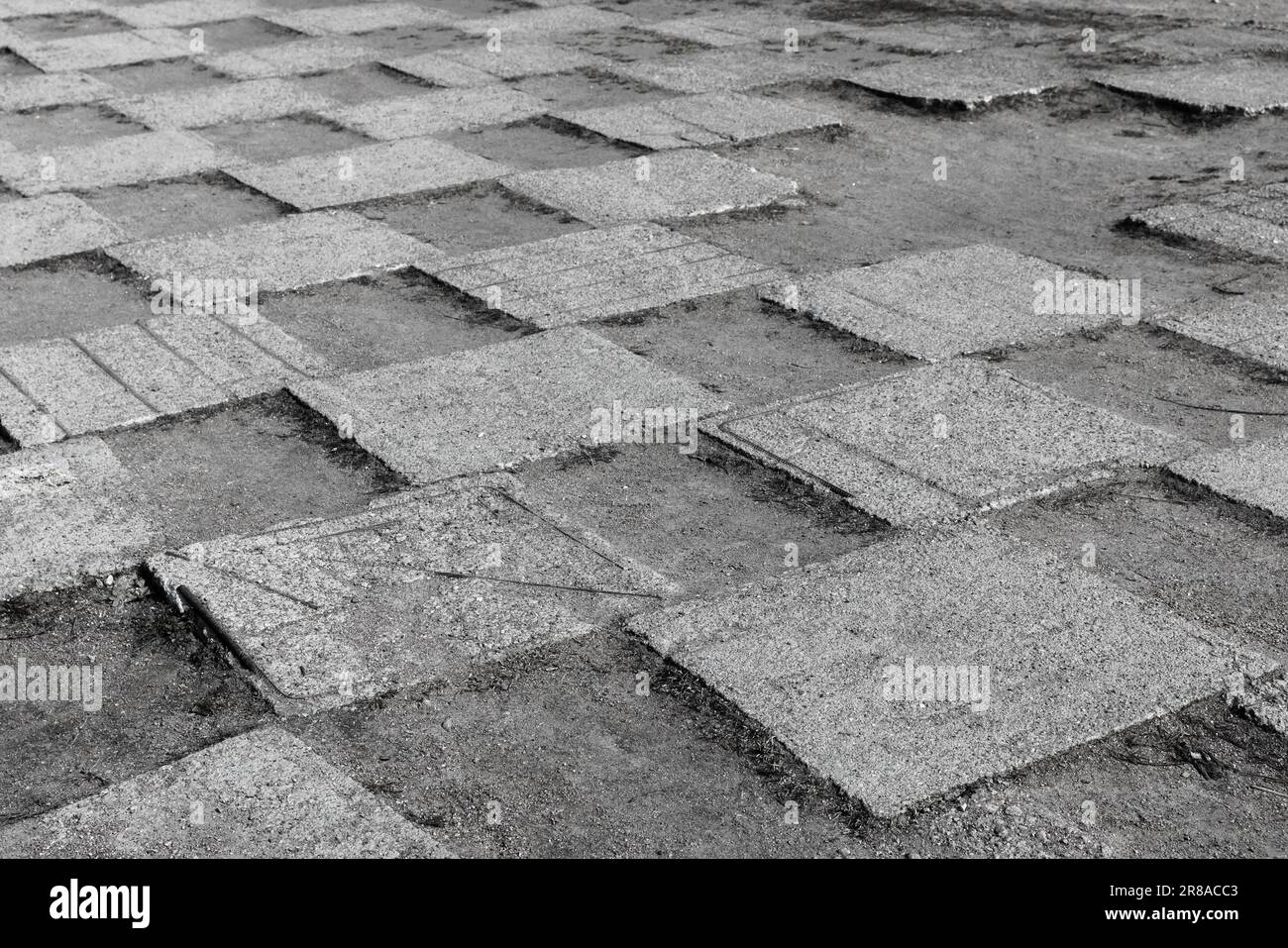 Graue Betonfliesen eines städtischen Bürgersteigs lagen auf staubigem Boden mit Schachbrettmuster, abstraktes Hintergrundfoto der Architektur Stockfoto