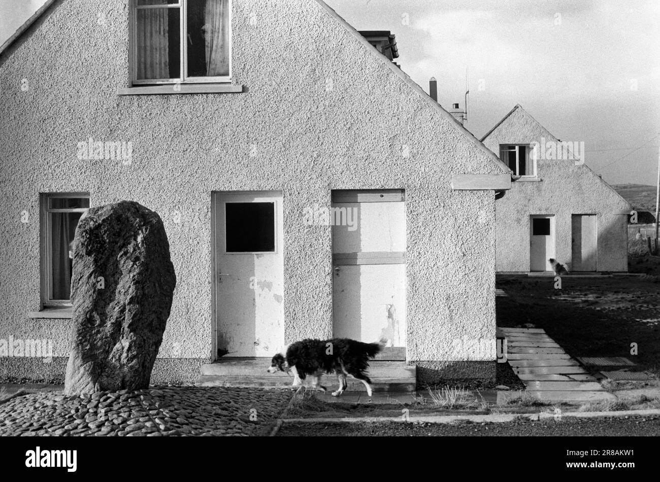 Callanisch, Isle of Lewis, Äußere Hebriden Schottland, ca. Juni 1974. Ein Randstein im Wohnungsbau des Stonefields council. Das ist Haus Nummer 14 Stonefield. Der Stein ist Callanish XII, Teil des riesigen Netzwerks, das diesen Bereich abdeckt und wahrscheinlich irgendwie auf den Mond ausgerichtet ist. 1970er Scotland UK HOMER SYKES Stockfoto