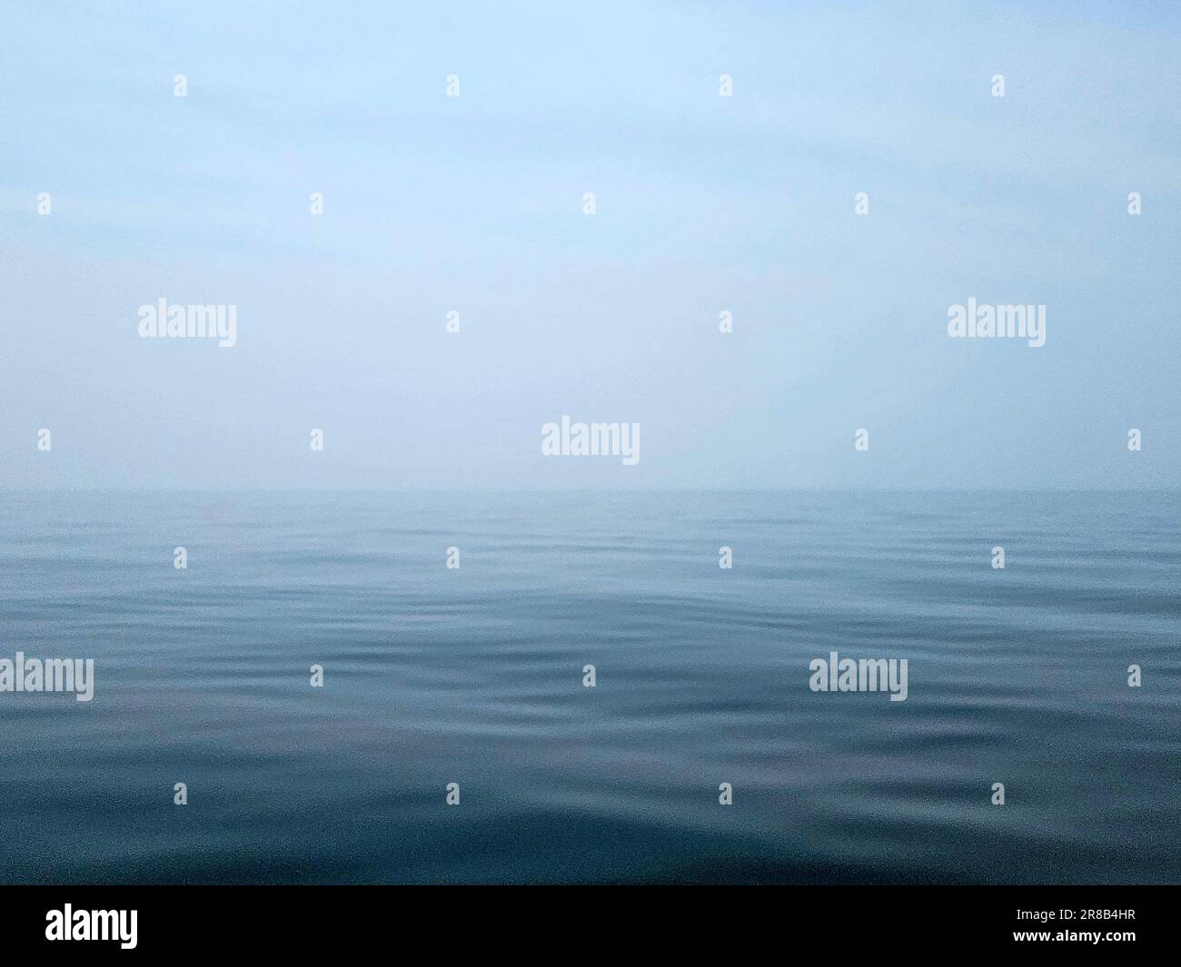 Ruhiges, blaues Wasser am Lake Michigan mit verschwommenem Horizont und Himmel Stockfoto