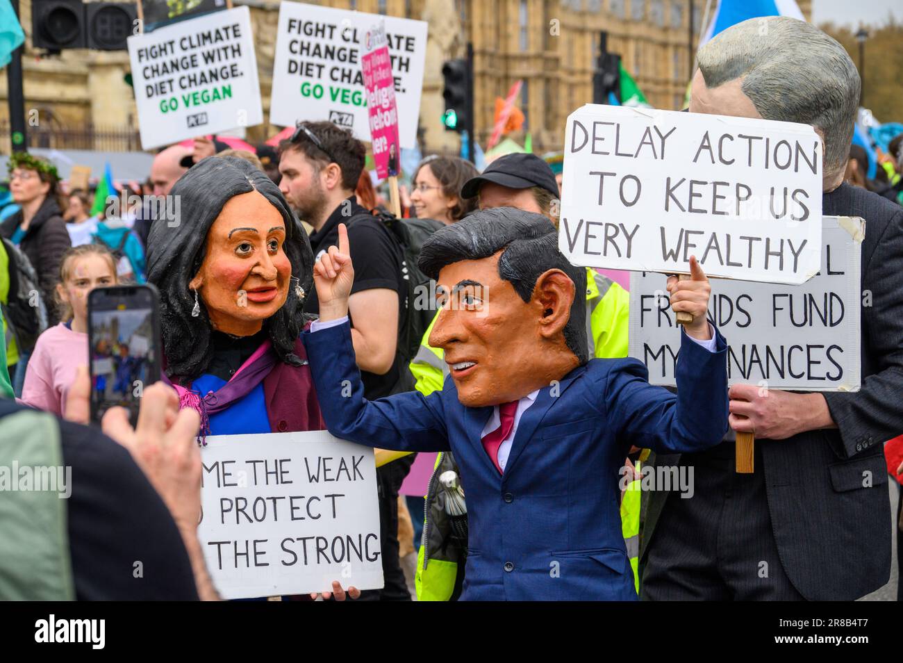 LONDON - 22. April 2023: Beeindruckende Szene, während XR-Demonstranten riesige Masken von Rishi Sunak und seiner Frau Akshata Murty tragen, die Zeichen für den Klimaschutz halten Stockfoto